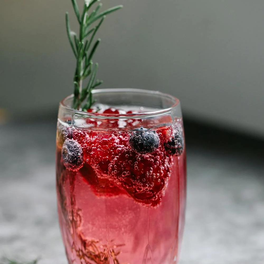 Sparkling water with cranberries and blueberries, red in color, providing a fruity and refreshing twist