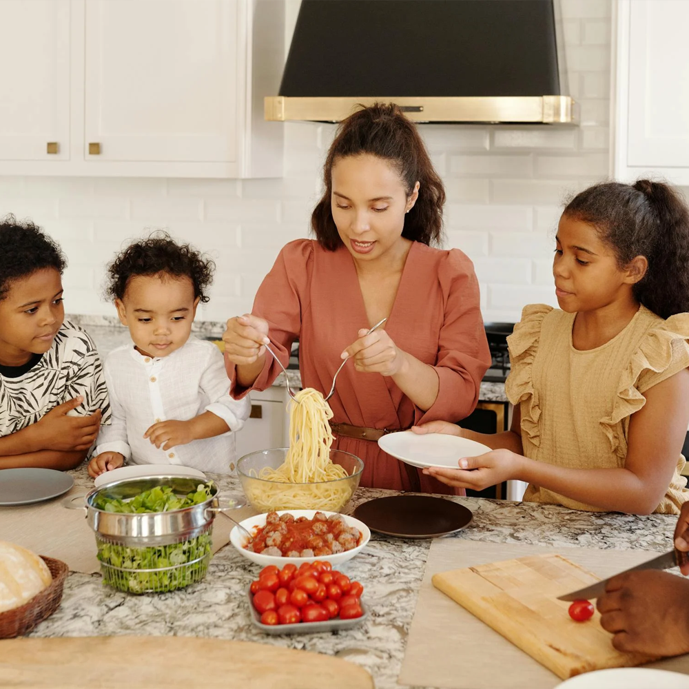 A mother cooking spaghetti with her children, sharing a fun and healthy meal preparation moment