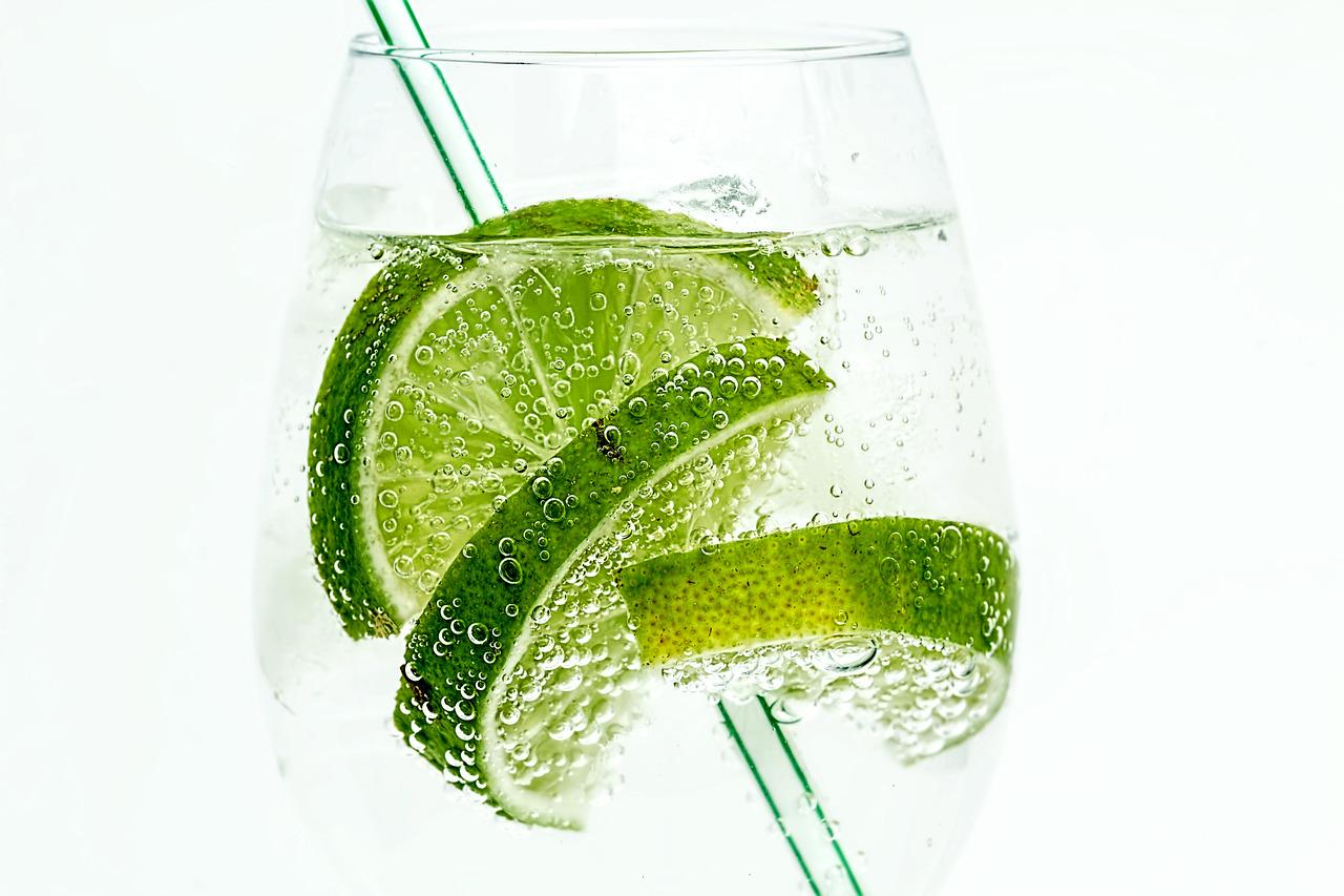 Close-up of a lime slice submerged in sparkling water, with small bubbles forming on its surface.