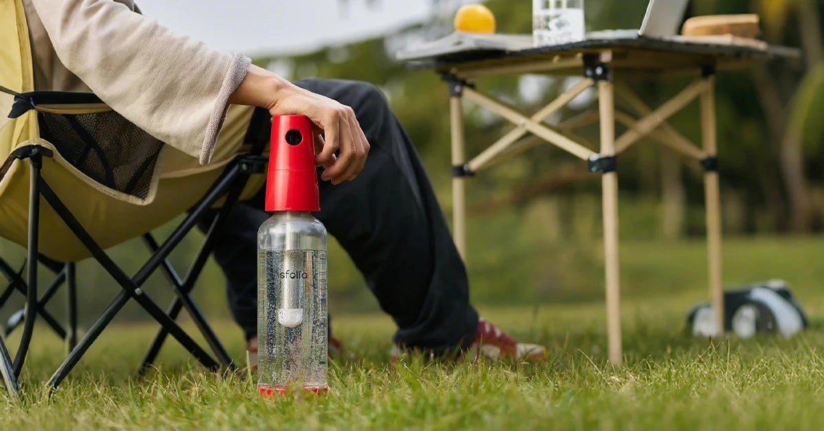 Person relaxing outdoors with an Asfolia sparkling water maker in a camping setting